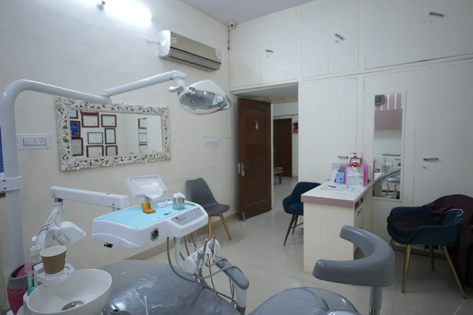 Dental treatment room with a chair, overhead light and wall mirror at Your Dentist, Malviya Nagar, Jaipur