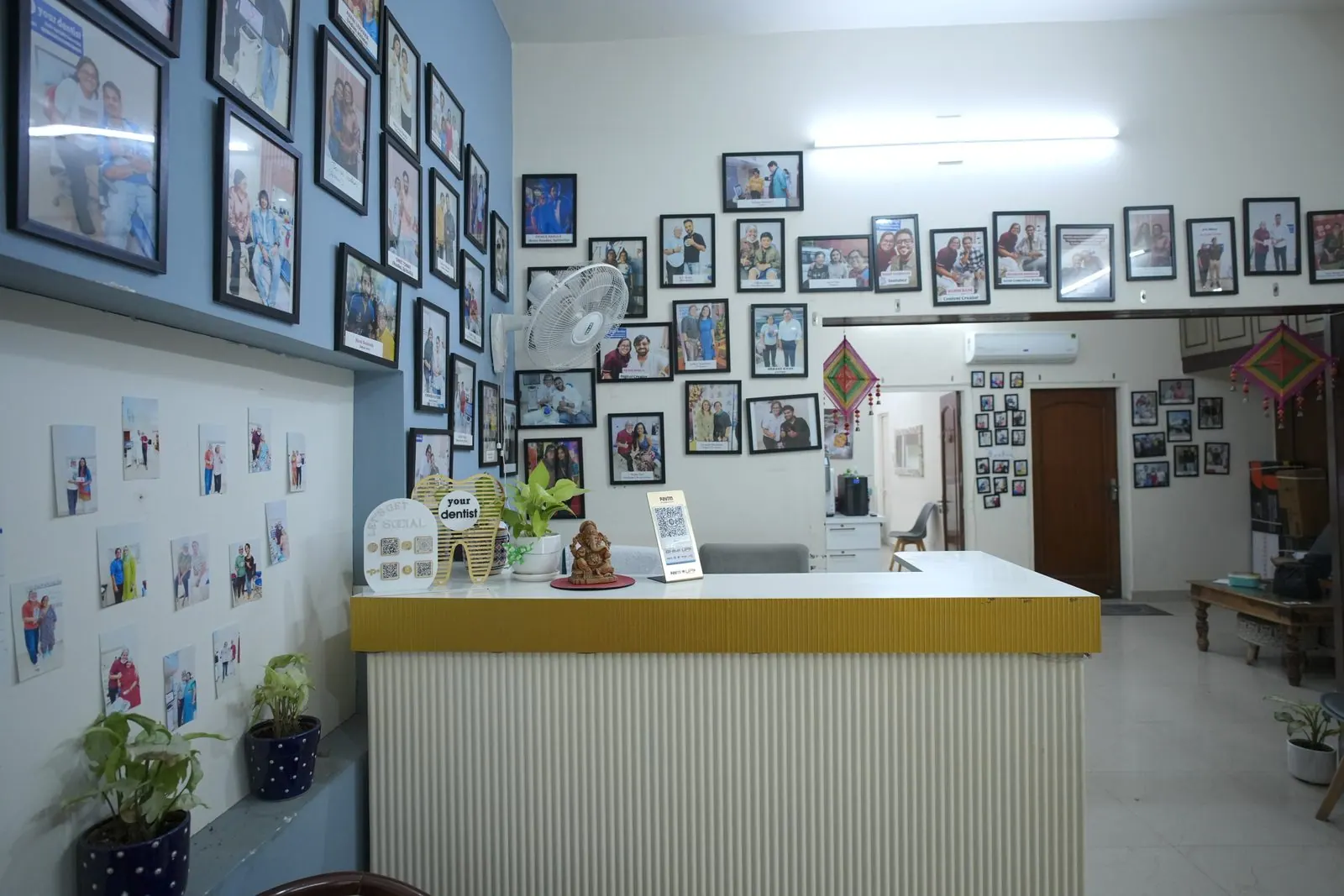 Reception counter with a wall of patient photos at Your Dentist, Malviya Nagar, Jaipur